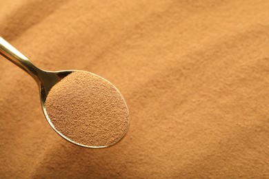 Photo of Spoon with aromatic instant coffee as background, closeup