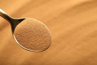 Photo of Spoon with aromatic instant coffee as background, closeup