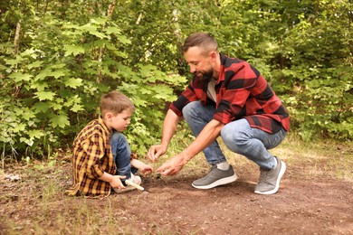 Photo of Father and his son planting tree into soil outdoors