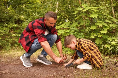 Photo of Father and his son planting tree into soil outdoors