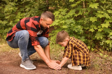 Photo of Father and his son planting tree into soil outdoors