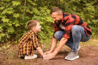 Photo of Father and his son planting tree into soil outdoors