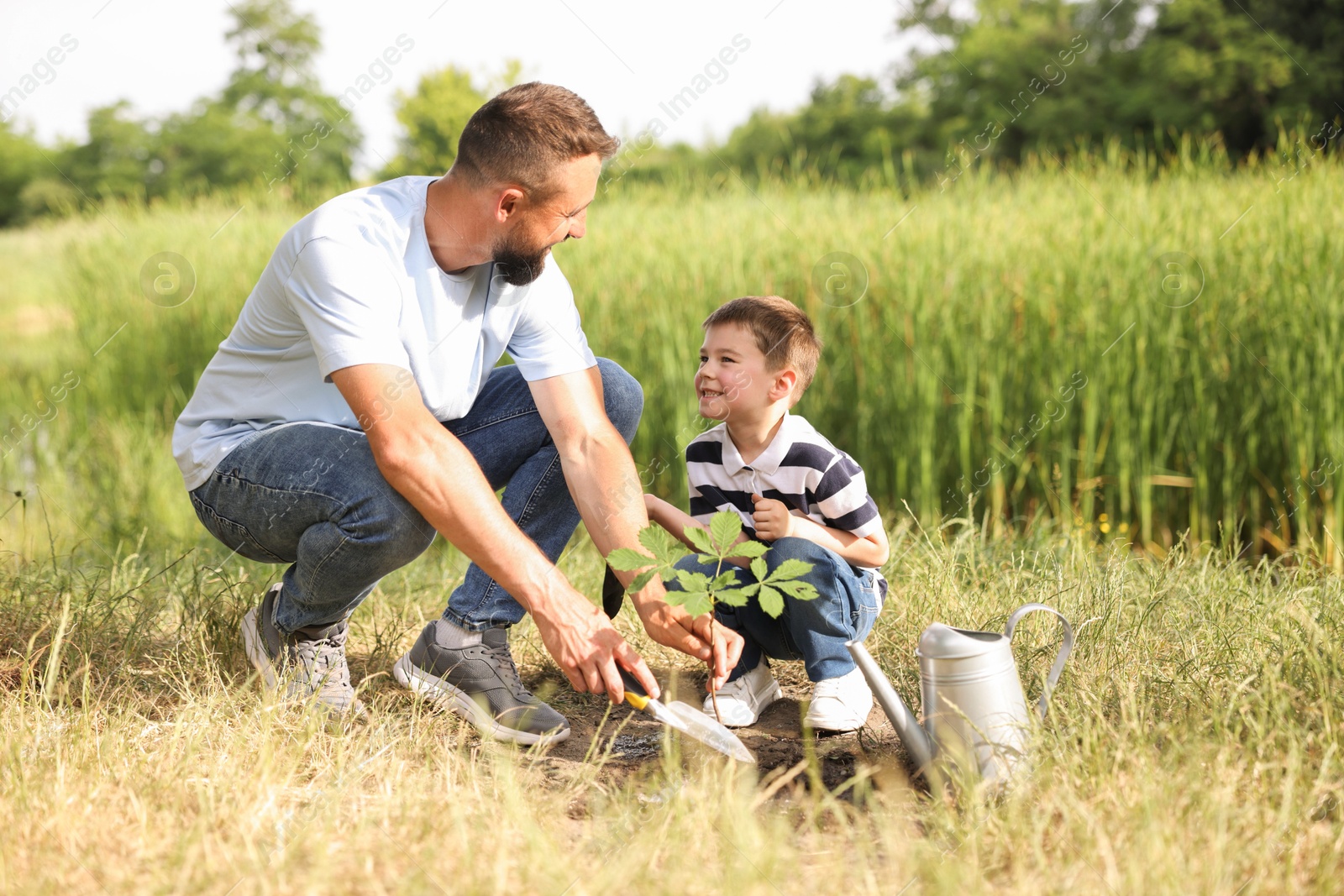 Father and his son planting tree into soil outdoors Photo of Father and his son planting tree into soil outdoors