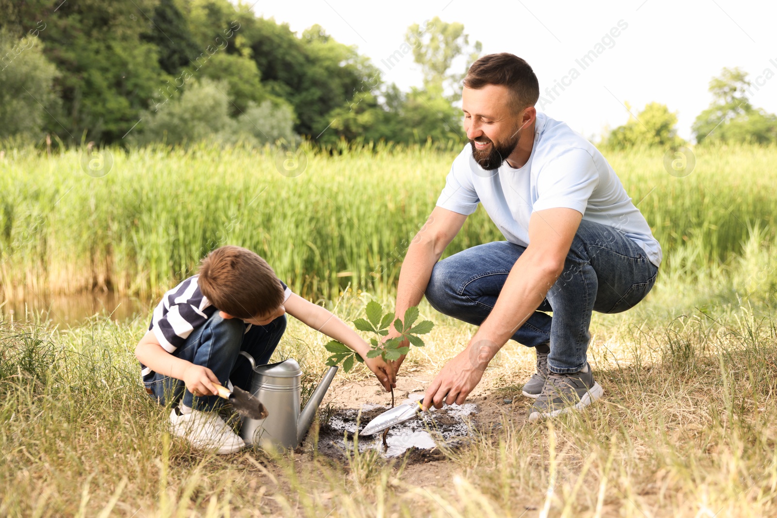 Father and his son planting tree into soil outdoors Photo of Father and his son planting tree into soil outdoors