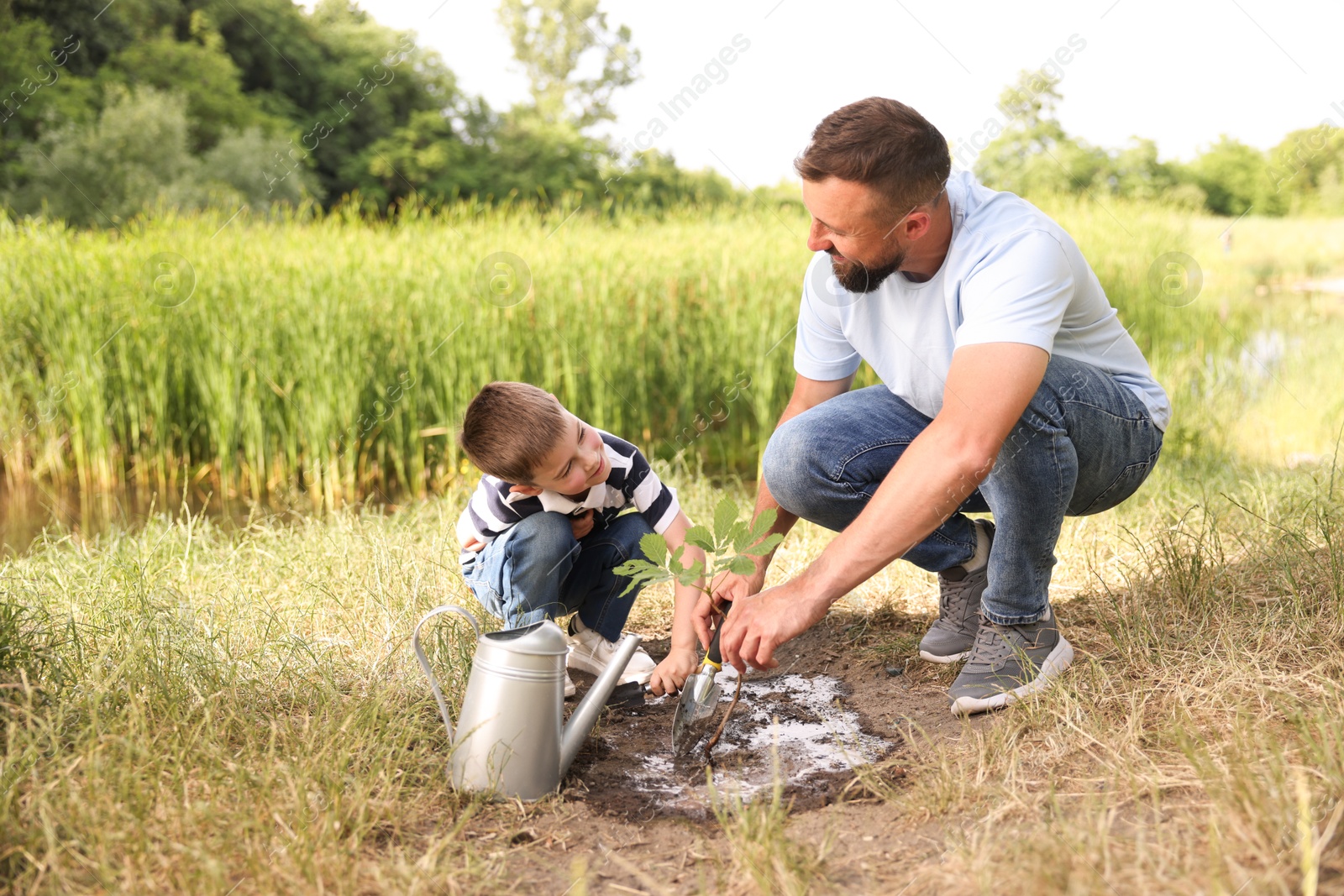 Father and his son planting tree into soil outdoors Photo of Father and his son planting tree into soil outdoors