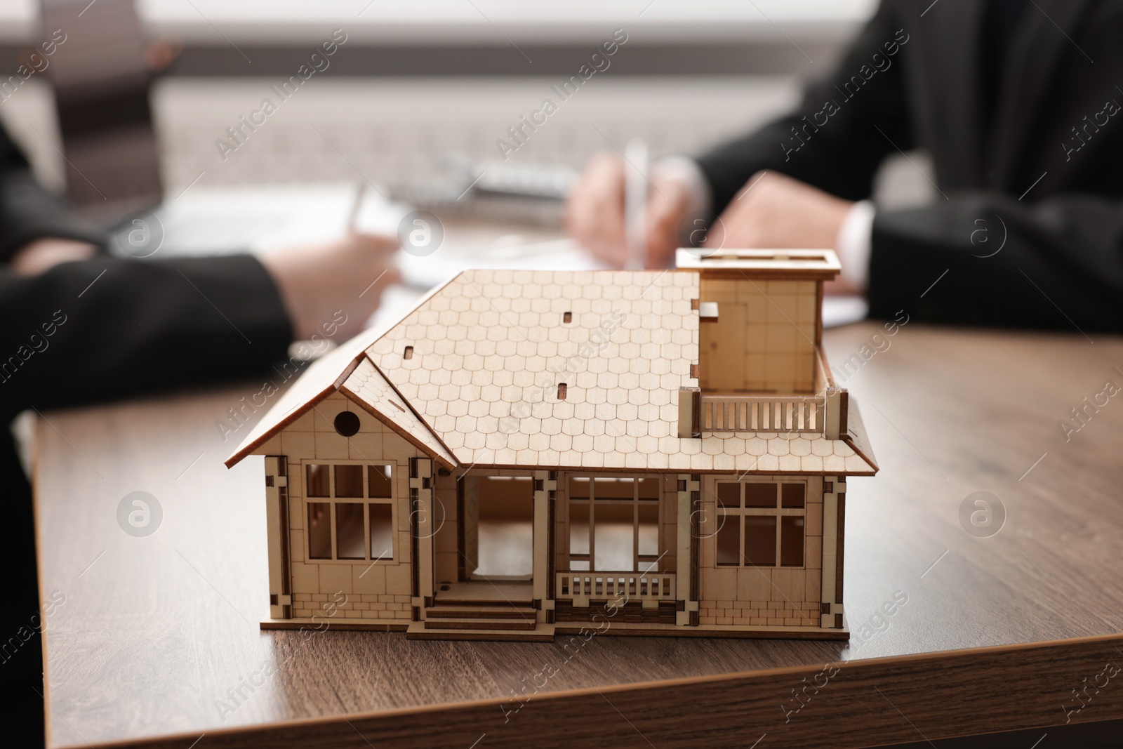 Real estate agent working with client at desk in office, focus on house model Photo of Real estate agent working with client at desk in office, focus on house model