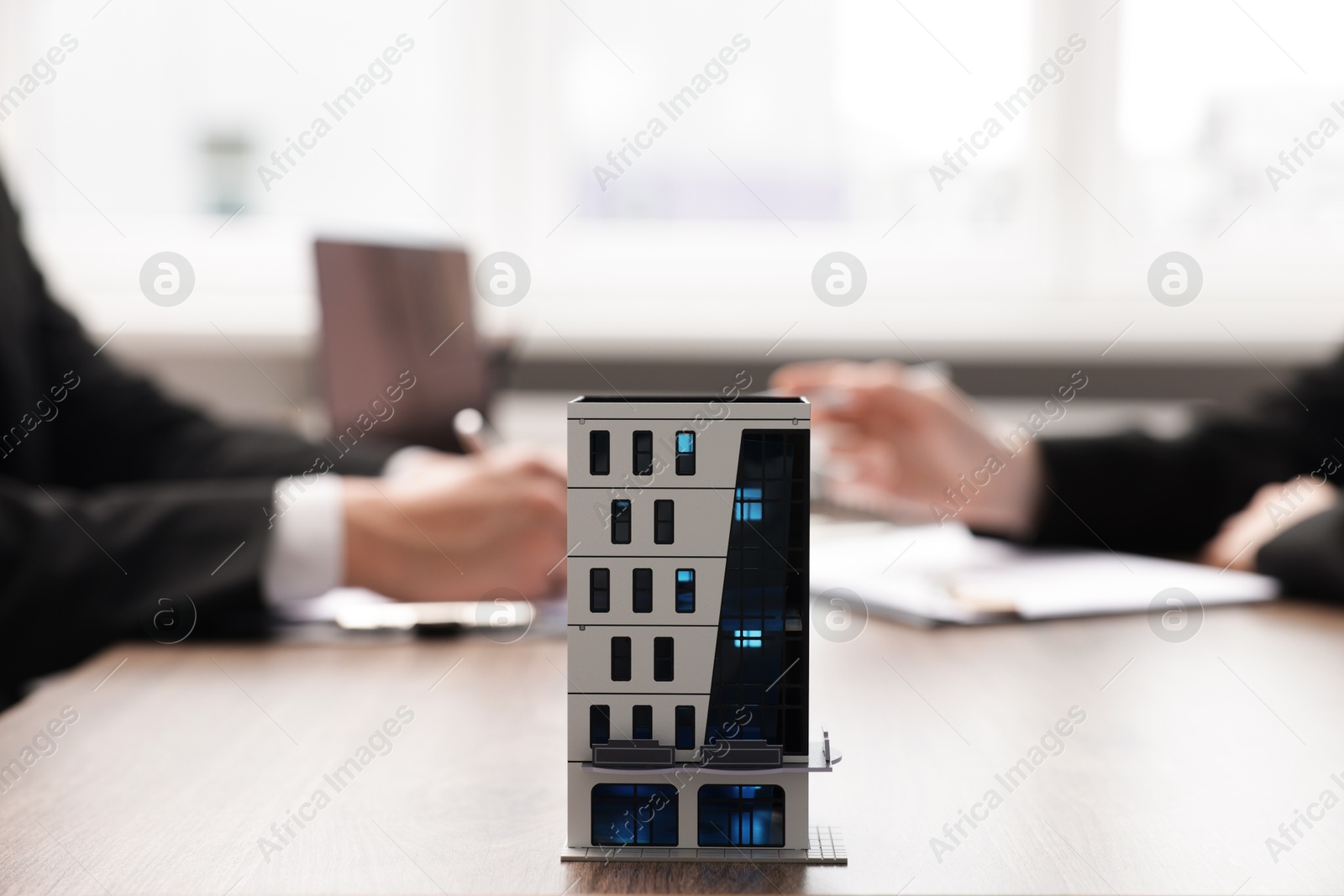 Real estate agent working with client at desk in office, focus on house model Photo of Real estate agent working with client at desk in office, focus on house model