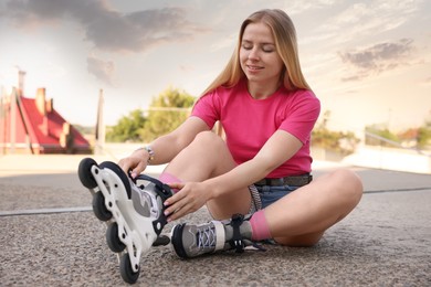Photo of Happy woman putting on roller skates outdoors