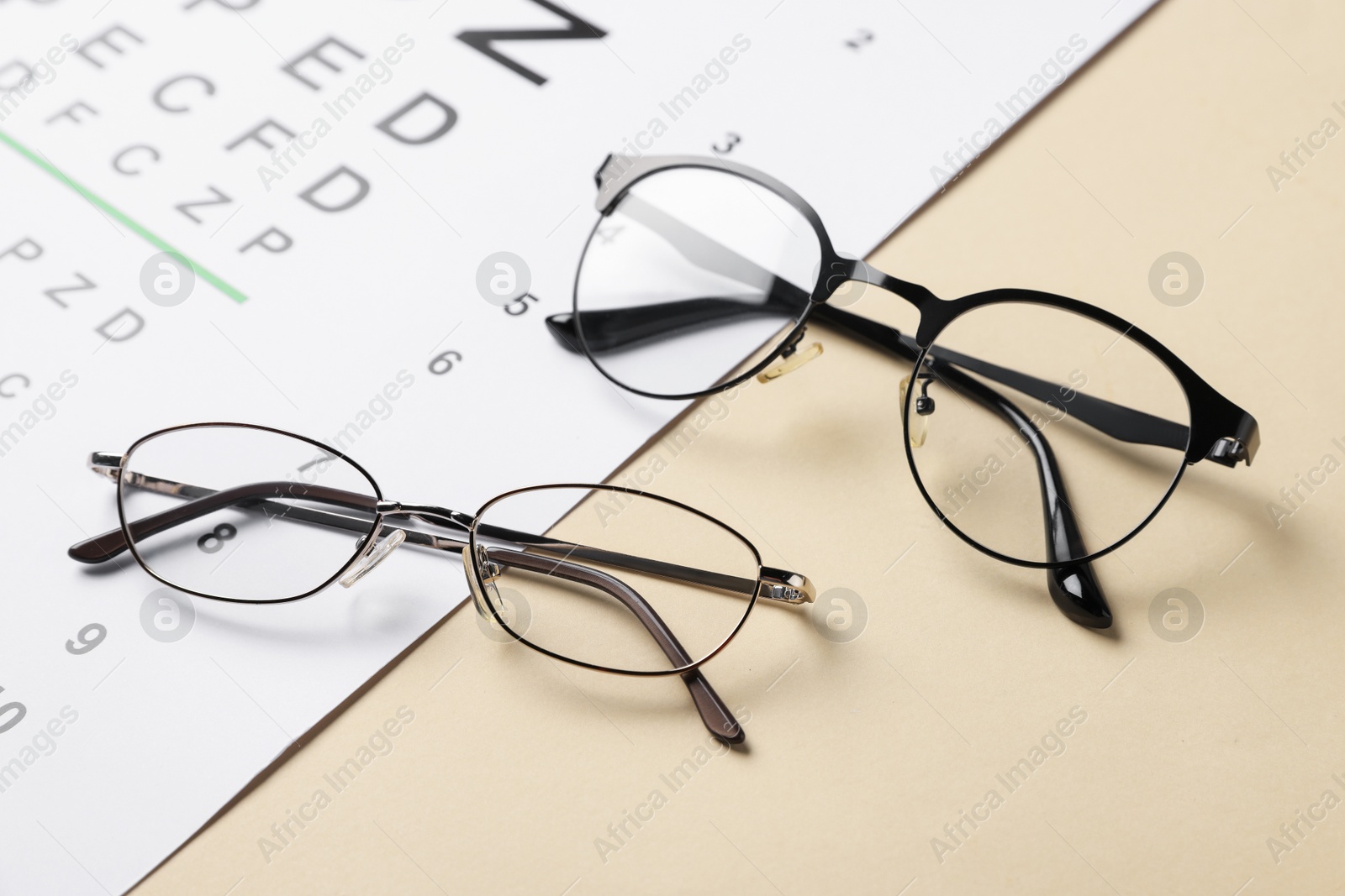 Photo of Vision test chart and glasses on beige background, closeup