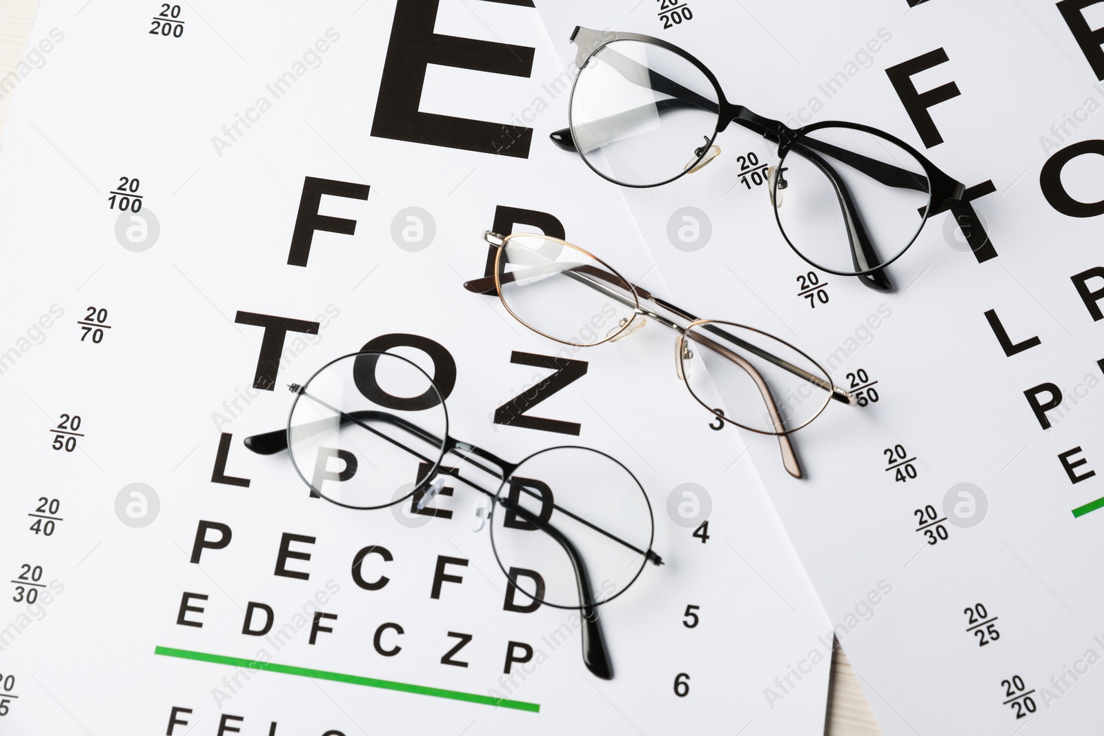 Photo of Glasses on vision test charts, flat lay