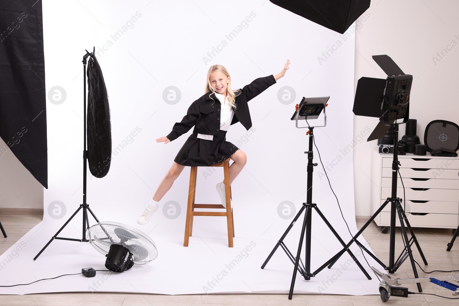 Little girl on white background in photo studio with professional equipment Photo of Little girl on white background in photo studio with professional equipment