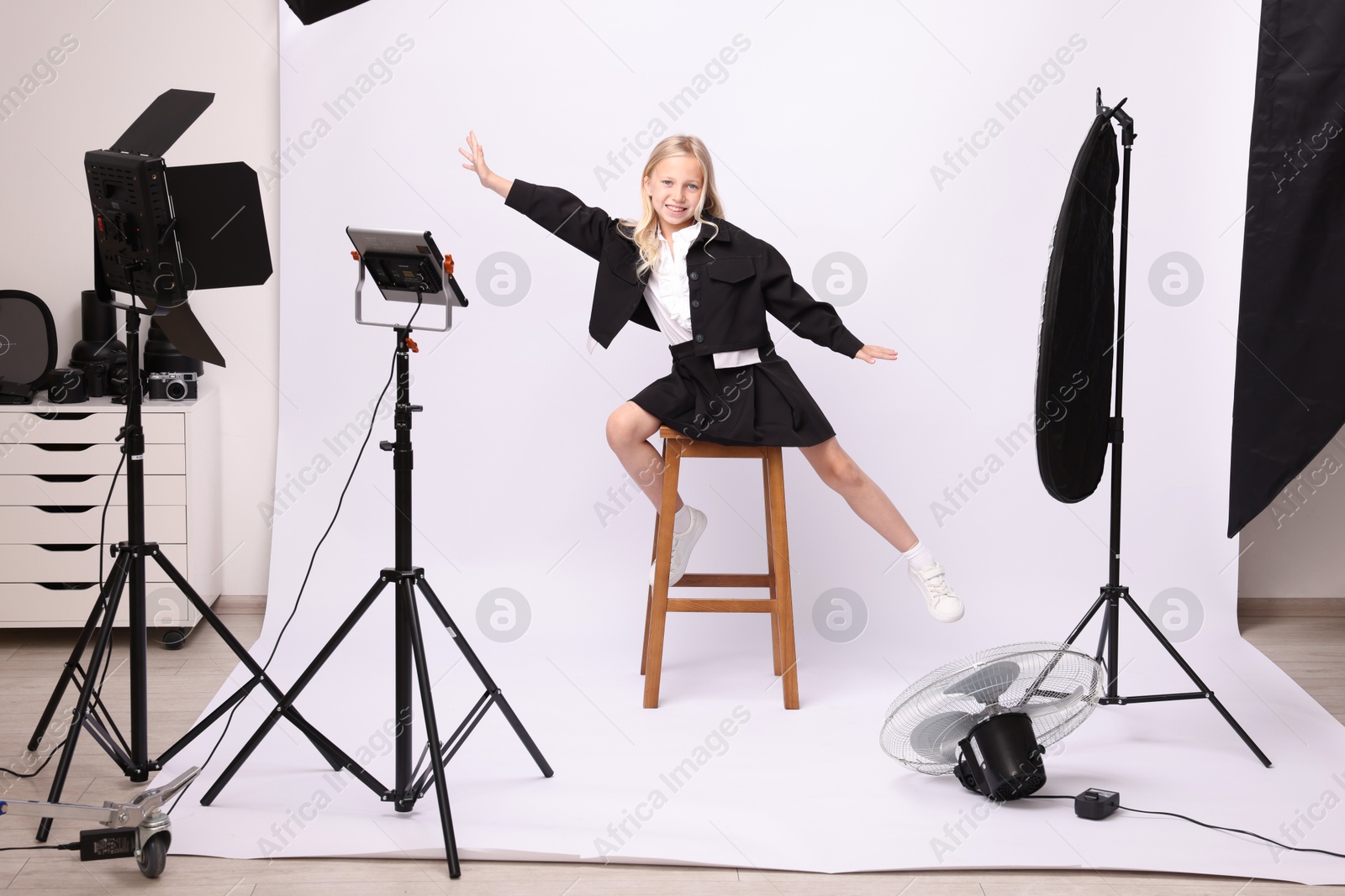 Little girl on white background in photo studio with professional equipment Photo of Little girl on white background in photo studio with professional equipment