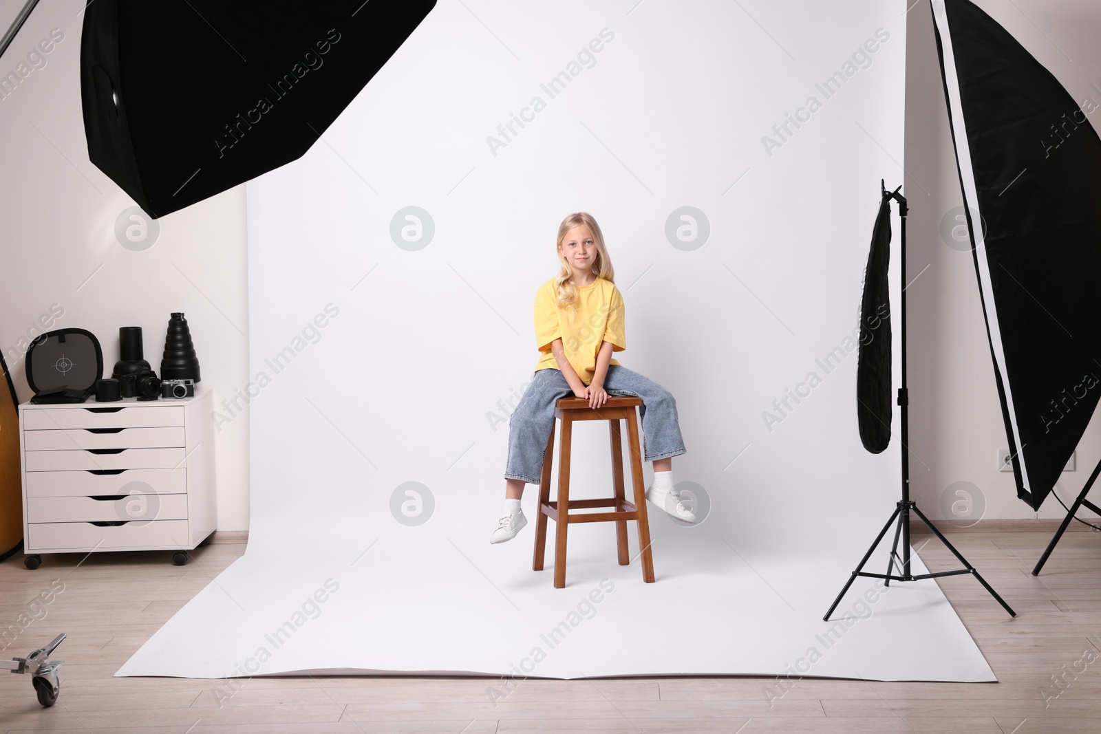 Little girl on white background in photo studio with professional equipment Photo of Little girl on white background in photo studio with professional equipment