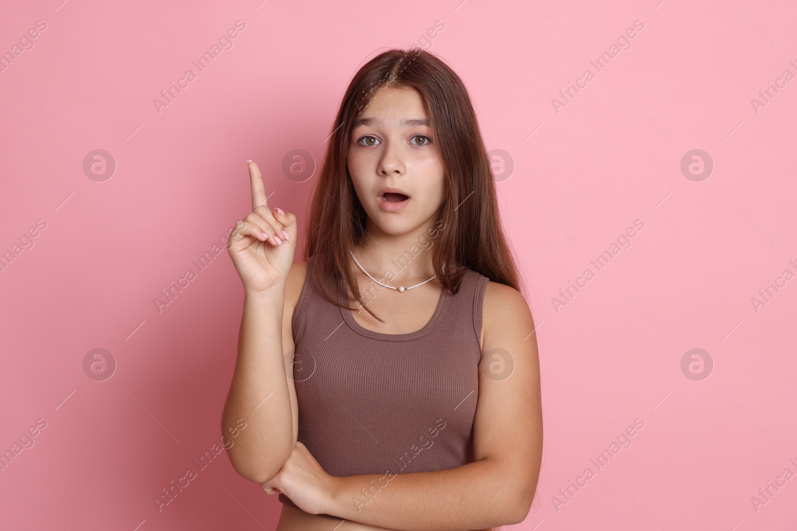 Photo of Teenage girl pointing at something on pink background