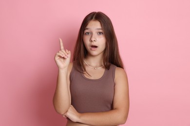 Photo of Teenage girl pointing at something on pink background