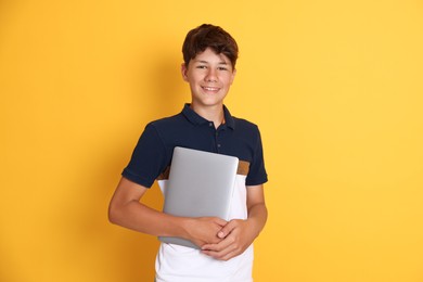 Photo of Teenage boy with laptop on orange background