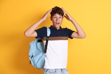 Photo of Teenage boy with backpack on orange background