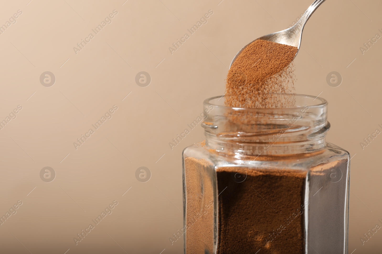 Photo of Taking instant coffee with spoon on beige background, closeup. Space for text
