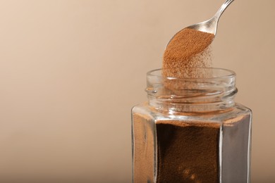 Photo of Taking instant coffee with spoon on beige background, closeup. Space for text