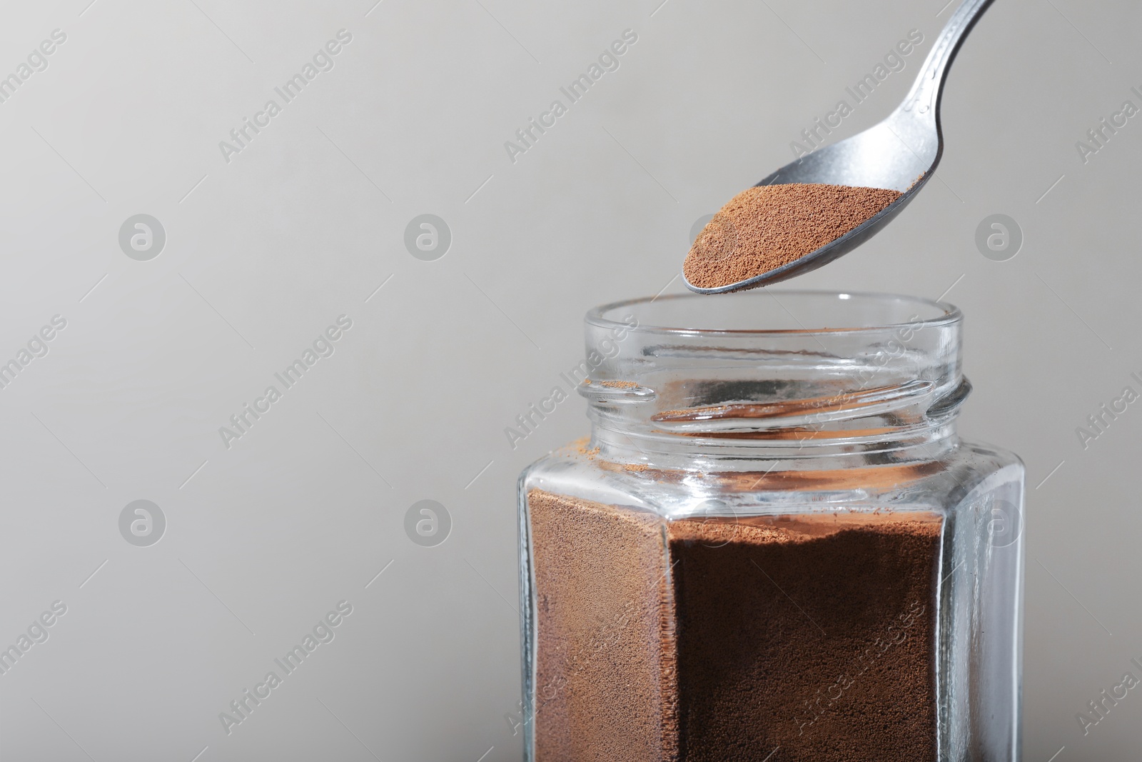 Taking instant coffee with spoon on grey background, closeup. Space for text Photo of Taking instant coffee with spoon on grey background, closeup. Space for text