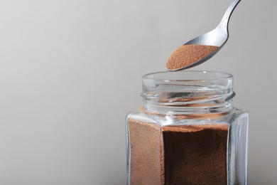 Photo of Taking instant coffee with spoon on grey background, closeup. Space for text