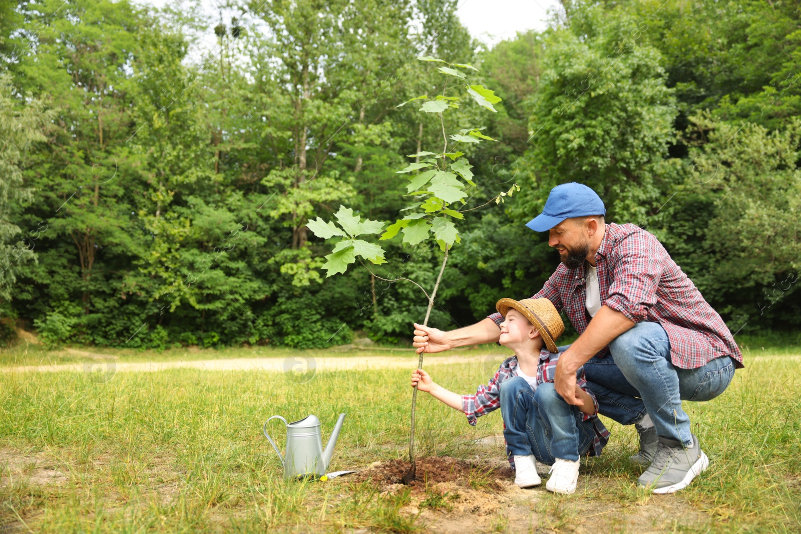 Father and his son planting tree into soil outdoors, space for text Photo of Father and his son planting tree into soil outdoors, space for text