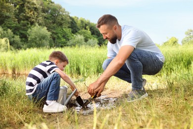 Photo of Father and his son planting tree into soil outdoors