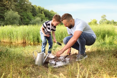 Photo of Father and his son planting tree into soil outdoors