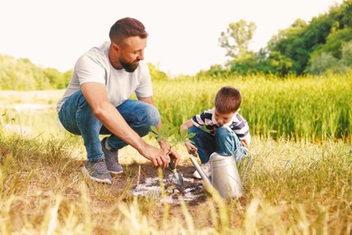 Photo of Father and his son planting tree into soil outdoors