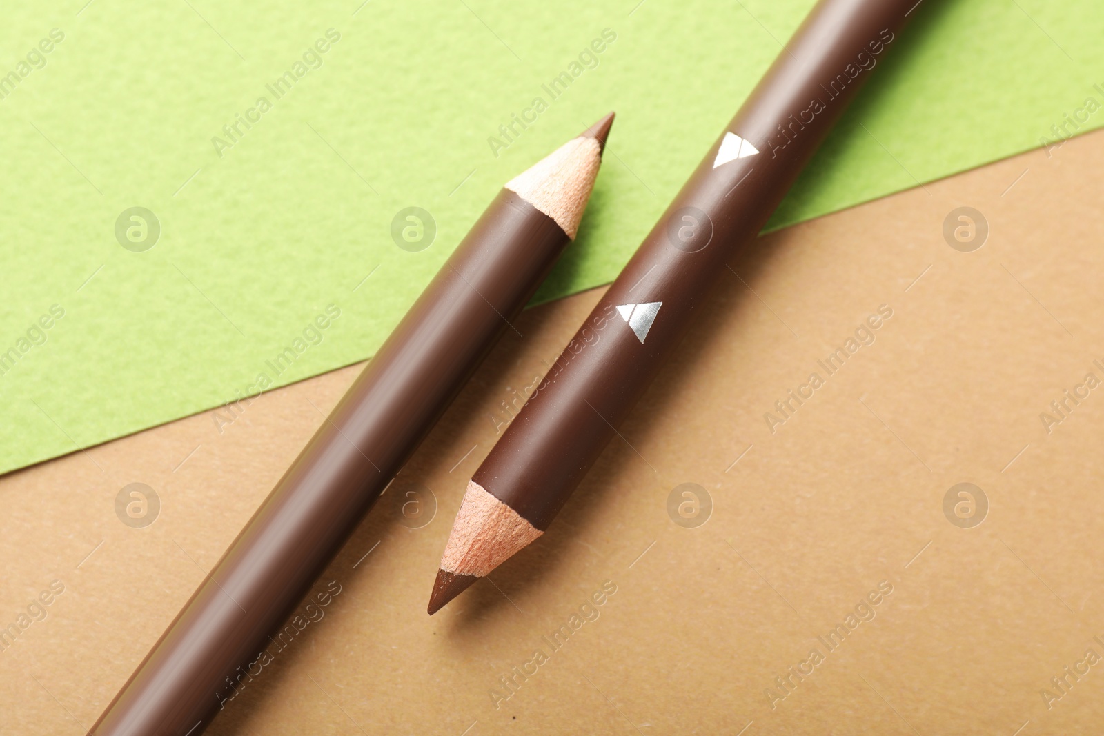 Brown eyebrow pencils on color background, flat lay Photo of Brown eyebrow pencils on color background, flat lay