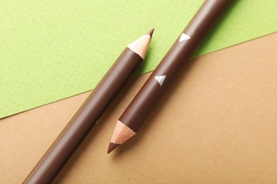 Photo of Brown eyebrow pencils on color background, flat lay