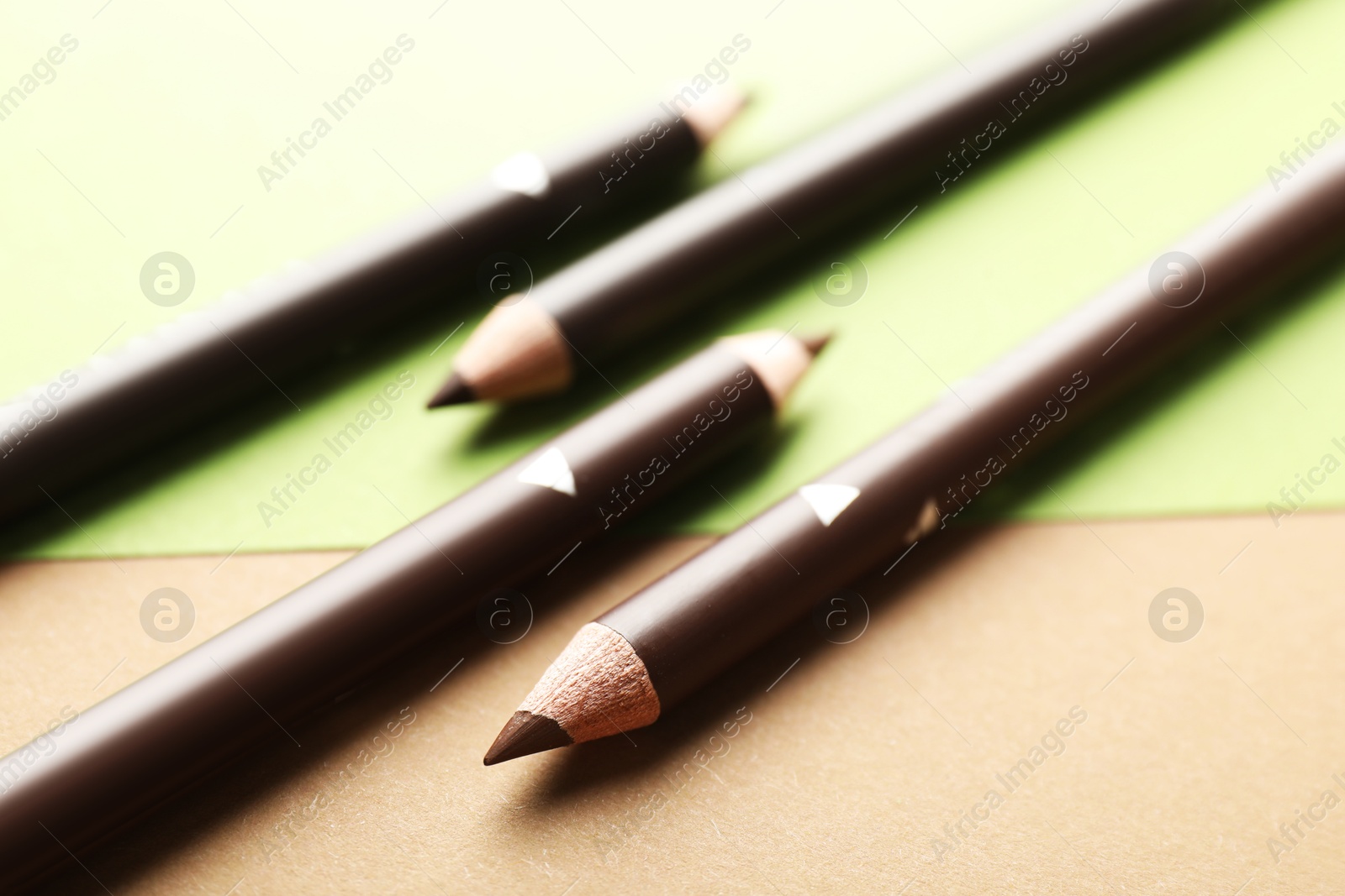 Photo of Brown eyebrow pencils on color background, closeup