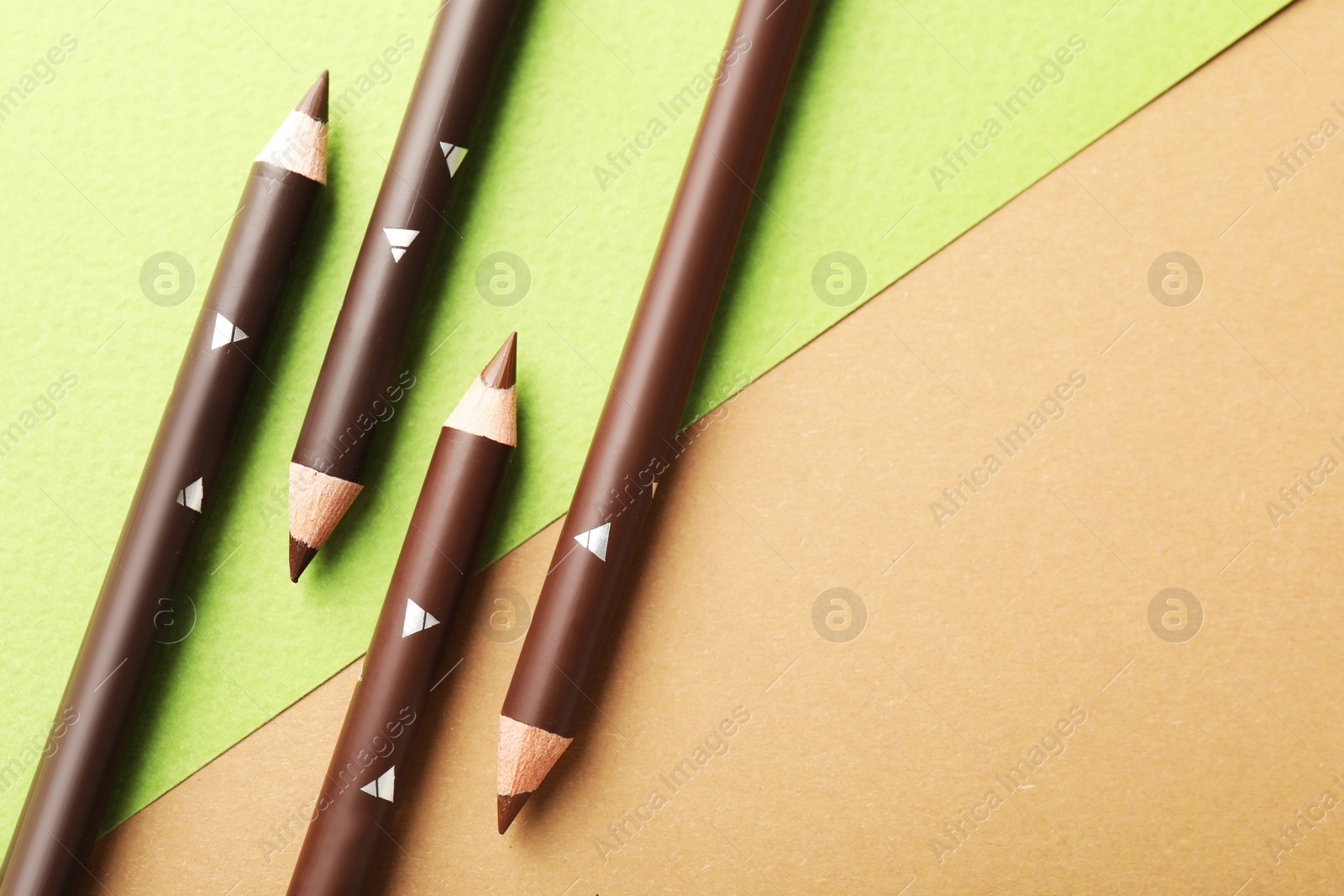 Brown eyebrow pencils on color background, flat lay. Space for text Photo of Brown eyebrow pencils on color background, flat lay. Space for text