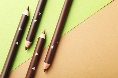 Photo of Brown eyebrow pencils on color background, flat lay. Space for text