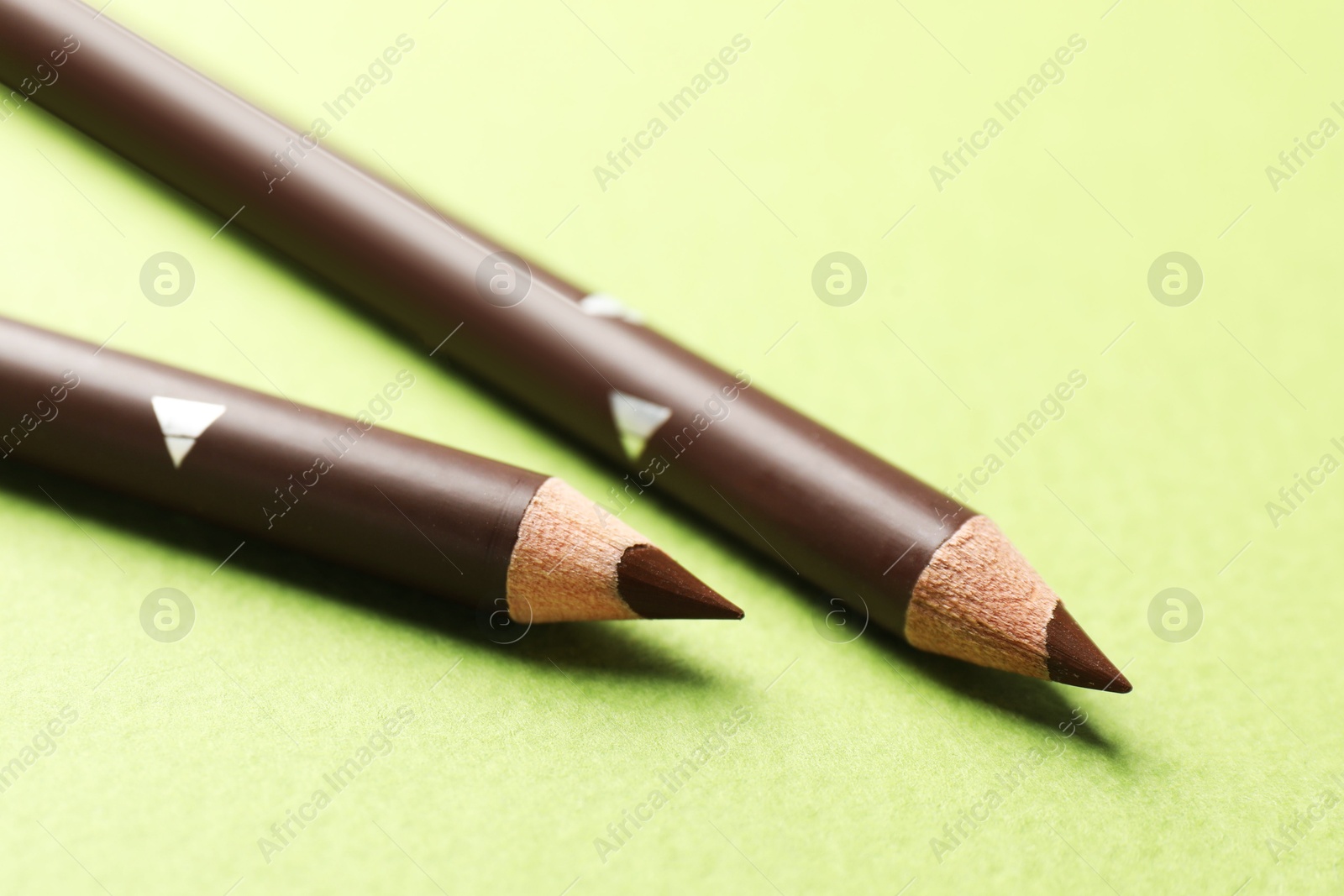 Brown eyebrow pencils on green background, closeup Photo of Brown eyebrow pencils on green background, closeup