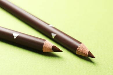 Photo of Brown eyebrow pencils on green background, closeup