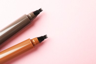 Photo of Liquid eyebrow pencils on light pink background, flat lay. Space for text