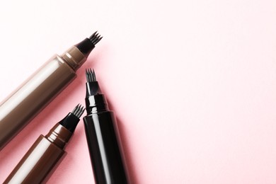 Photo of Liquid eyebrow pencils on light pink background, flat lay. Space for text