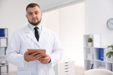 Photo of Doctor with tablet in clinic, space for text. Online medical consultation