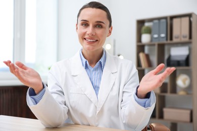 Photo of Portrait of happy doctor in uniform at table indoors