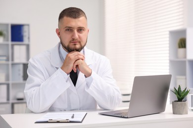 Photo of Doctor working at table with laptop in clinic. Online medical consultation