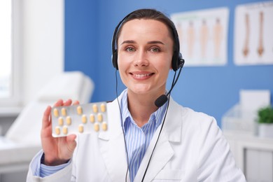Photo of Doctor with headset and pills having online consultation in clinic