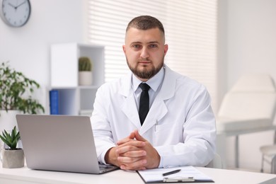 Photo of Doctor working at table with laptop in clinic. Online medical consultation