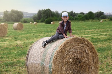 Photo of Little boy on hay bale in field at summer