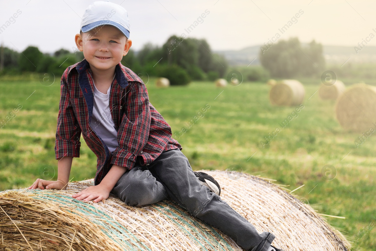 Little boy on hay bale in field at summer. Space for text Photo of Little boy on hay bale in field at summer. Space for text