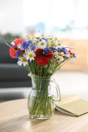 Photo of Beautiful wildflowers in vase and book on wooden table at home