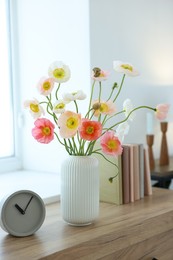 Photo of Beautiful poppy flowers, clock and books on wooden table indoors