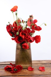 Photo of Beautiful red poppy flowers in vase on wooden table against white background