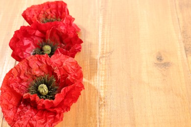 Photo of Beautiful red poppy flowers on wooden table, closeup. Space for text