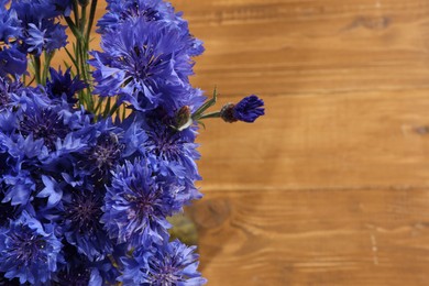 Photo of Beautiful blue cornflowers on wooden table, closeup. Space for text